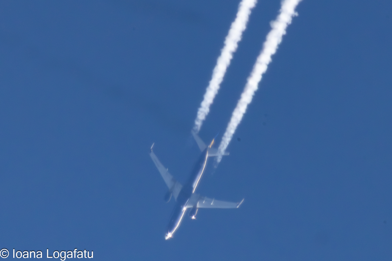 High flying jet leaves trails in the blue sky